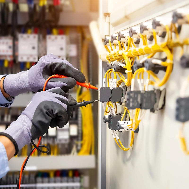 Électricien testant des circuits électriques avec un multimètre.