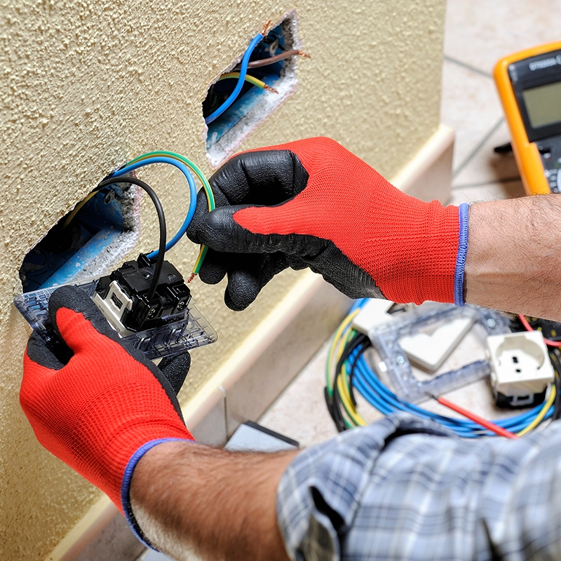 Technicien installant des fils électriques dans une prise murale.