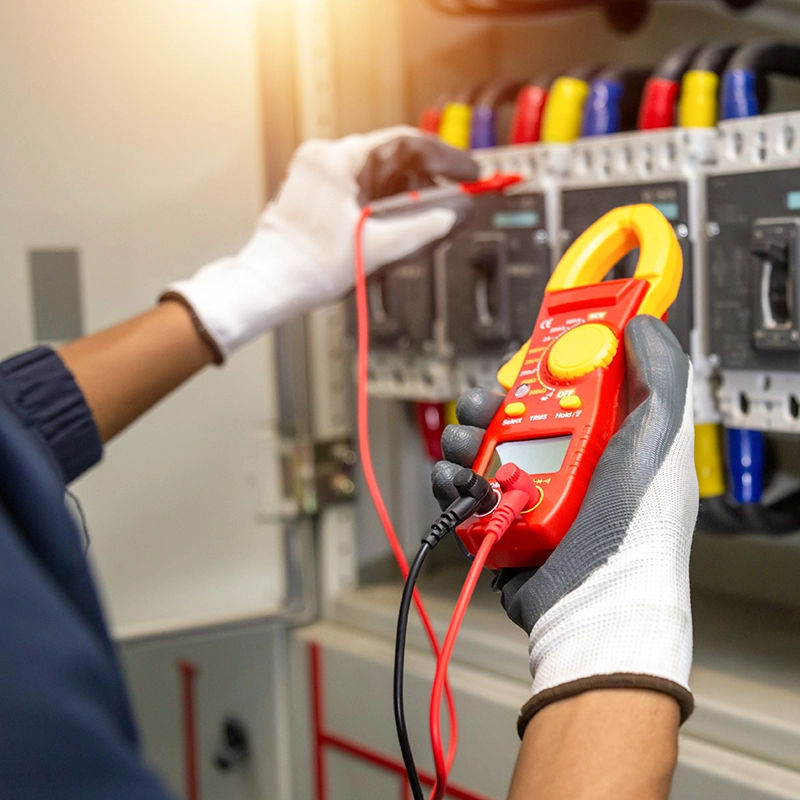 Technicien vérifiant une installation électrique avec un multimètre.