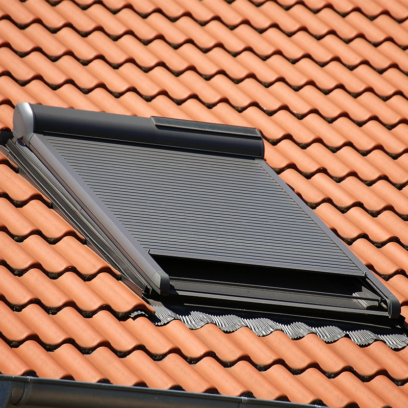 Fenêtre Velux motorisée installée sur un toit en tuiles.